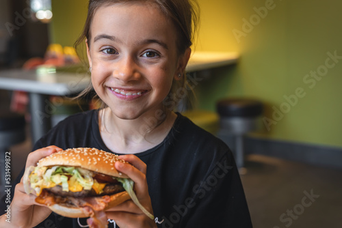 A little girl eats an appetizing burger  close-up.