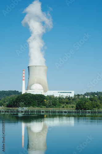 Nuclear power plant on the Rhine river bank. Leibstadt, Switzerland Smoke is rising from the cooling tower. It reflects on the water.