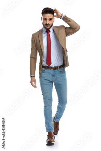 pensive young man with red tie holding hand up and scratching head