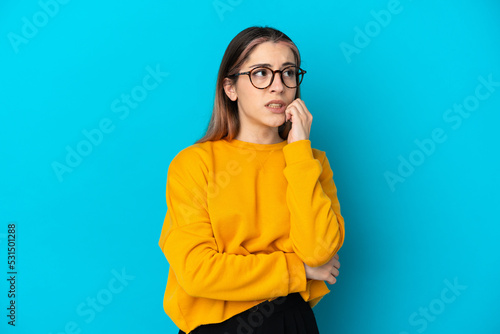 Young caucasian woman isolated on blue background is a little bit nervous