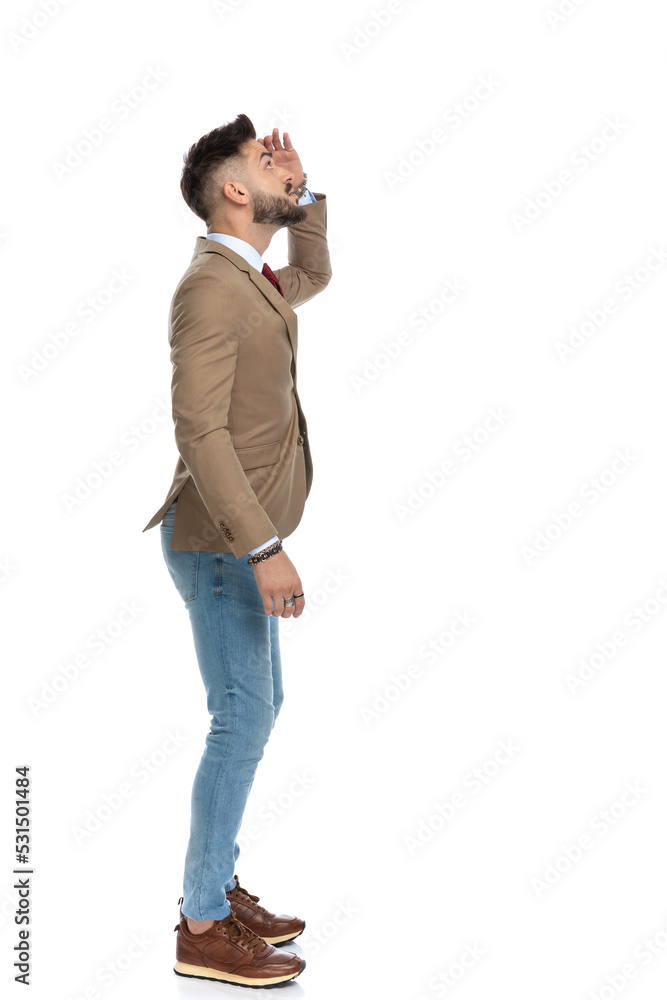 side view of curious young man holding hand to forehead and looking side view of curious young man holding hand to forehead and looking