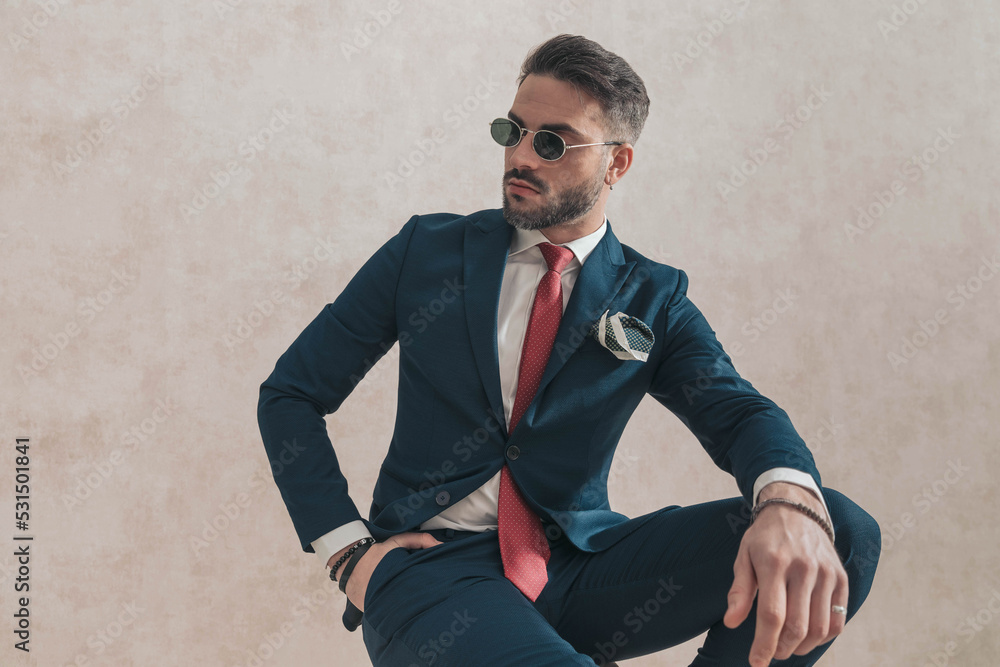 handsome unshaved man in stylish outfit with hand in pocket looking to side