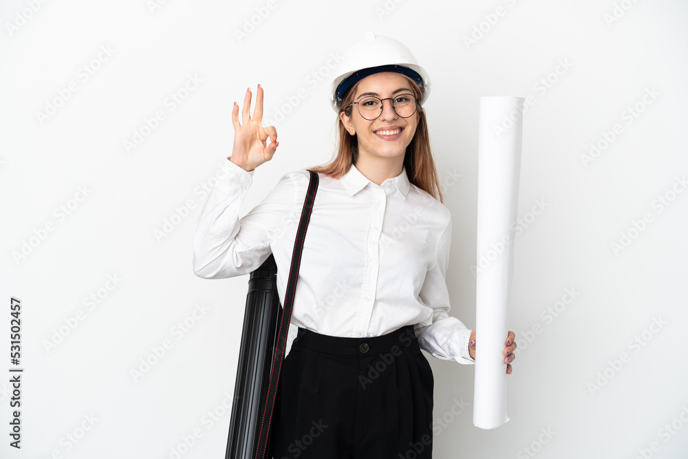 Young architect woman with helmet and holding blueprints isolated on white background showing ok sign with fingers Young architect woman with helmet and holding blueprints isolated on white background showing ok sign with fingers