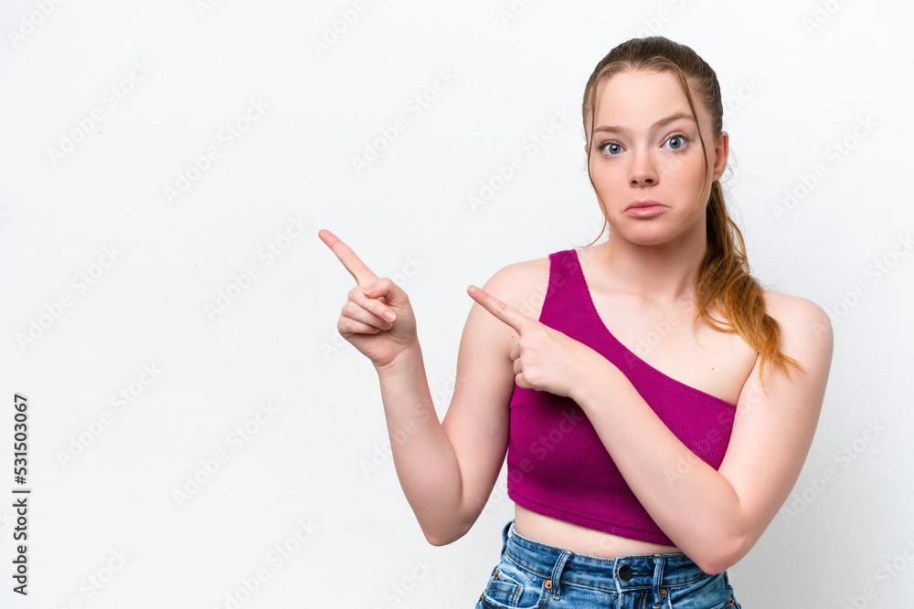 Young caucasian girl isolated on white background frightened and pointing to the side Young caucasian girl isolated on white background frightened and pointing to the side