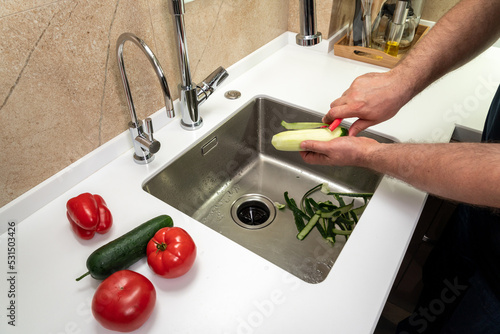Cleaning vegetables in the kitchen in the sink by a man