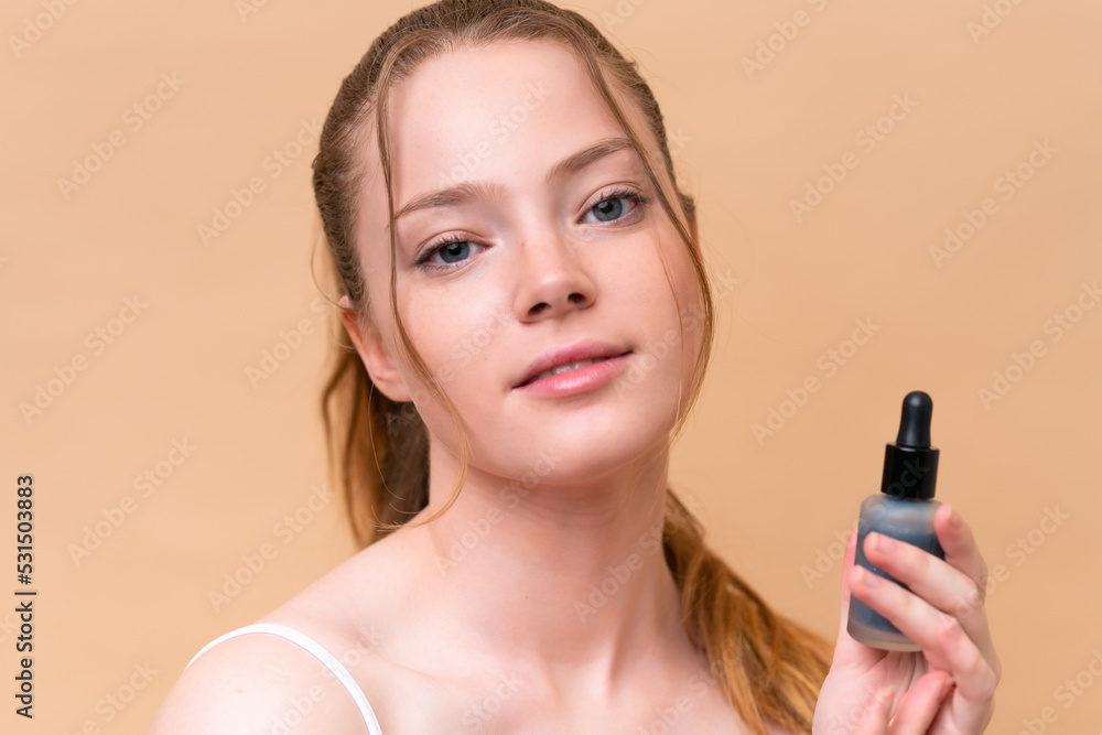 Young caucasian girl isolated on beige background holding a serum. Close up portrait Young caucasian girl isolated on beige background holding a serum. Close up portrait