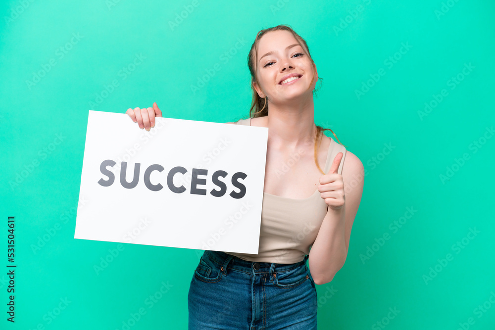 Young caucasian woman isolated on green background holding a placard with text SUCCESS with thumb up Young caucasian woman isolated on green background holding a placard with text SUCCESS with thumb up