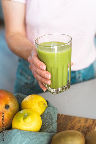 Unrecognizable female hand holding a glass of fresh green healthy smoothie.