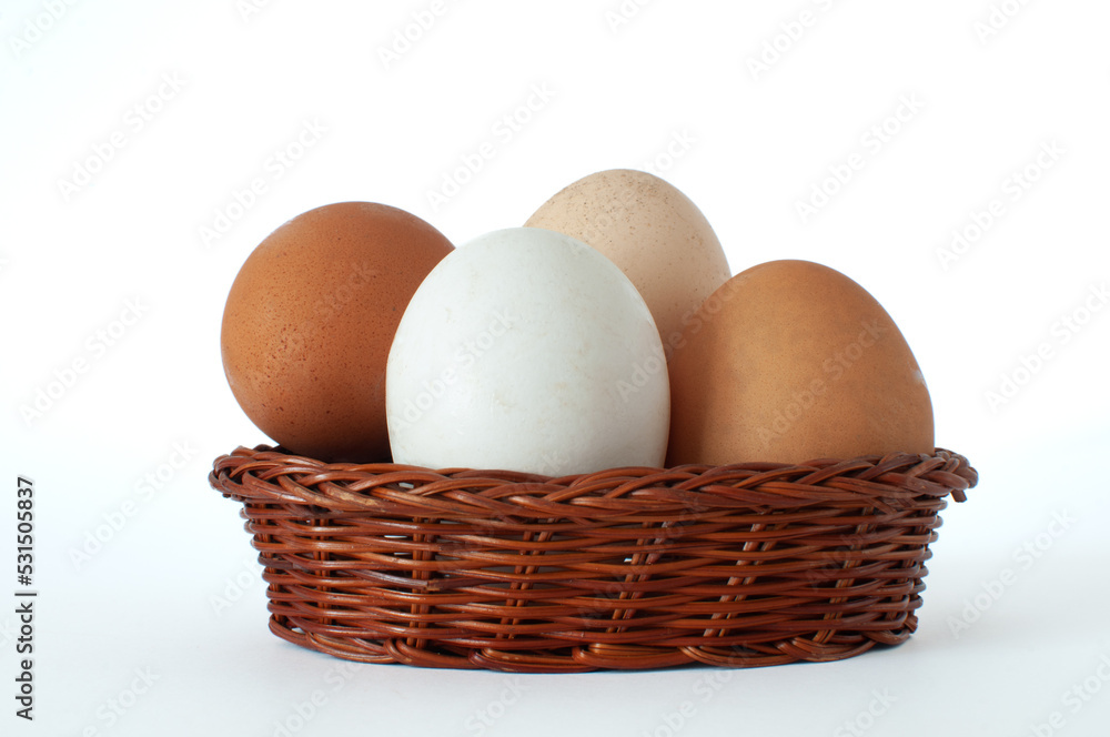 Collection of white, brown and light brown organic farm chicken eggs in mini brown wicker basket and isolated on white background. Collection of white, brown and light brown organic farm chicken eggs in mini brown wicker basket and isolated on white background.
