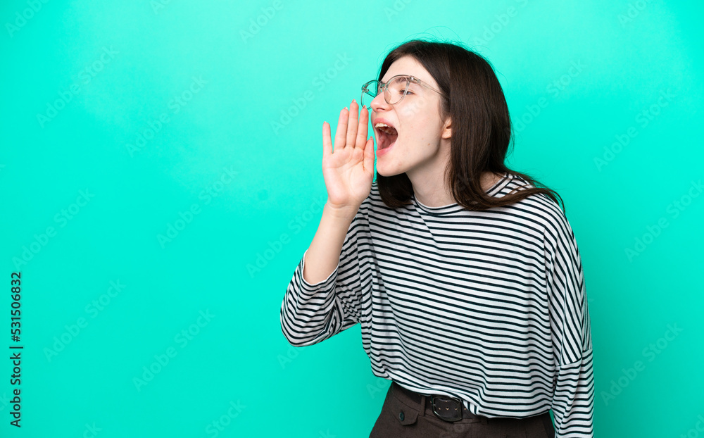 Young Russian woman isolated on green background shouting with mouth wide open to the side Young Russian woman isolated on green background shouting with mouth wide open to the side
