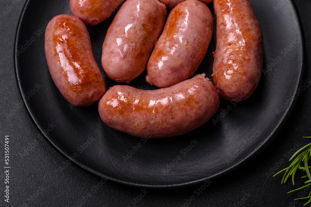 Grilled sausages with spices and herbs on a black background Grilled sausages with spices and herbs on a black background