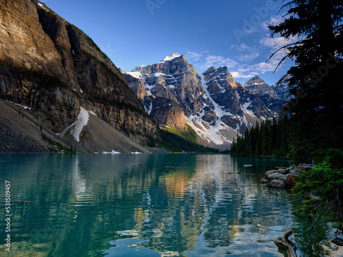 On the shore of Moraine Lake in Banff with the three sisters reflected in the calm lake waters