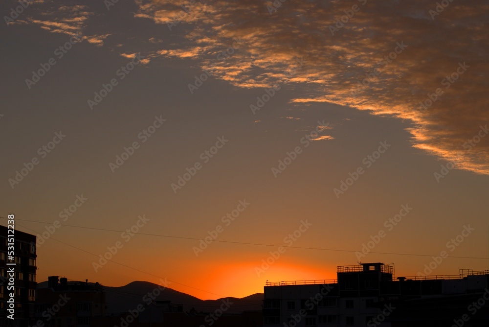 Sunrise from behind the mountains against the backdrop of urban new buildings