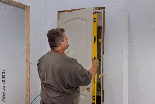 An employee leveling interior doors of new house during installation the doors is checking whether correct installation door is being installed