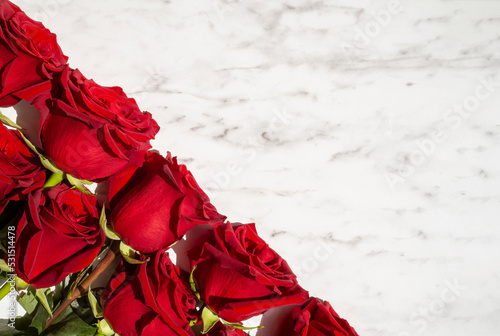 Red roses on marble background. Greeting card for holiday text. Top view, flat lay