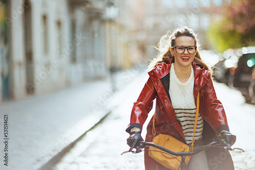 smiling stylish woman outdoors on city street riding bicycle