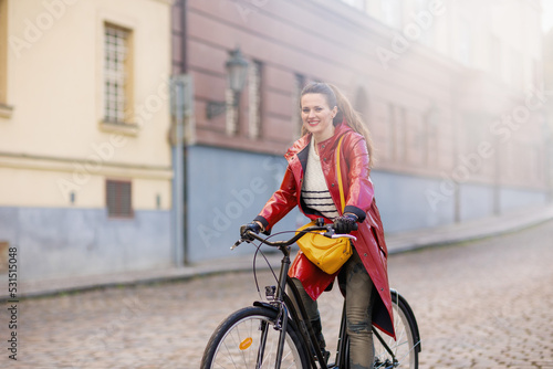 smiling modern woman outdoors on city street riding bicycle