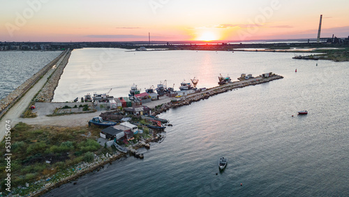 Aerial view of a harbor with boats sailing and docked. Photography was taken from a drone at a higher altitude in summer season at sunset.