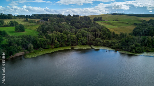 Views of a Scottish lake, green trees and meadows from above.
