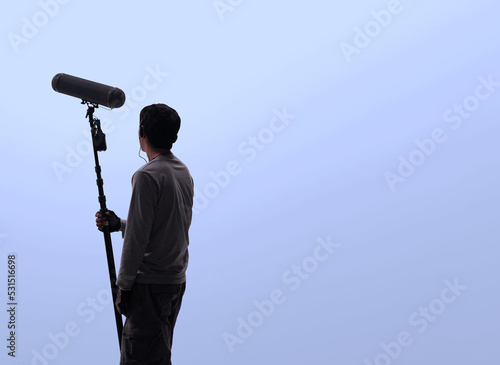 Boom Microphone for sound recording in film industry. Sound boom operator recording sound by microphone fisher for movie set in studio. Boom mic holds up high by video or film production crew team man photo
