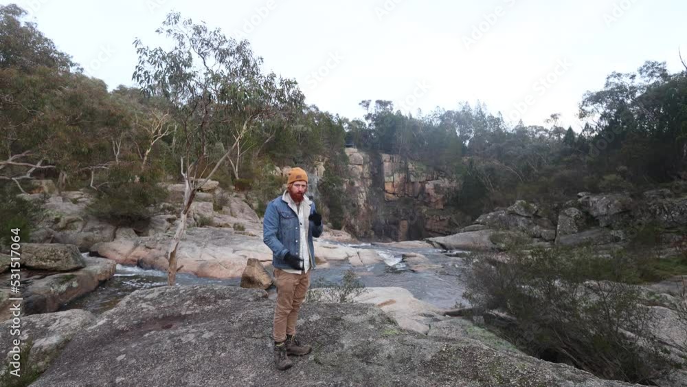 A bushman smoking a pipe and putting gloves on in the cold australian bush ontop of a waterfall. A bushman smoking a pipe and putting gloves on in the cold australian bush ontop of a waterfall.