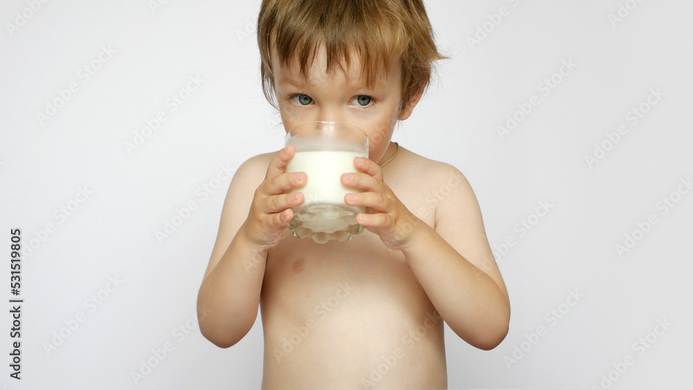 A cute boy drinking milk from a glass against white background A cute boy drinking milk from a glass against white background