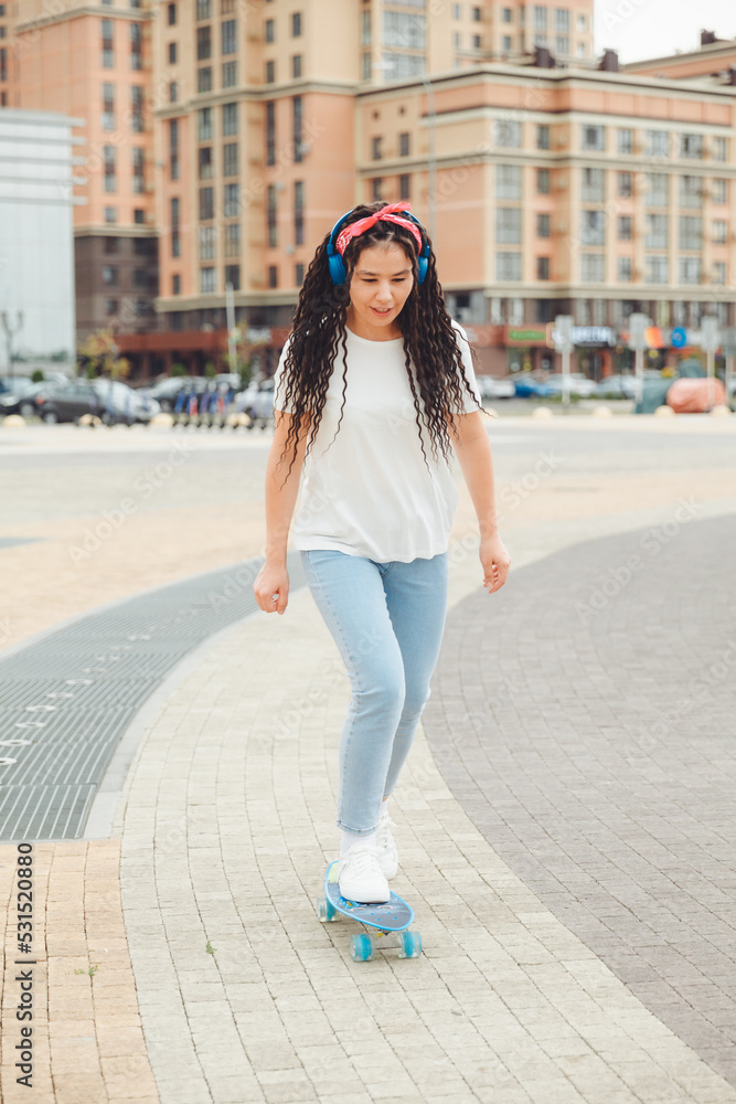 Fototapeta premium A beautiful young girl with dreadlocks rides a skateboard in sunny weather. generation z