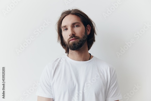 Portrait of a man with a black thick beard and long hair in a white T-shirt on a white isolated background lifestyle without pathos everyday image