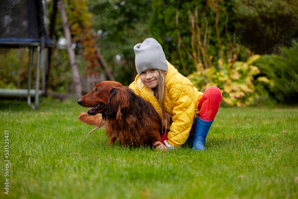 Little girl in autumn with a dog on the grass