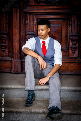 Obraz na płótnie Young Man sitting on stairs by wooden office door in New York City, taking work break. w salonie