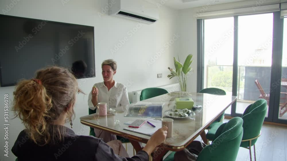lunch in the office, two women, colleagues talking at a large table in the office, a positive company. There is no time for a restaurant. lunch in the office, two women, colleagues talking at a large table in the office, a positive company. There is no time for a restaurant.