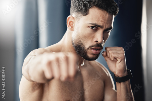 Fist, hand and boxing portrait of man, athlete and strong boxer training, exercise and workout in a gym or fitness club. Motivation, health and young fighting professional working on sports endurance
