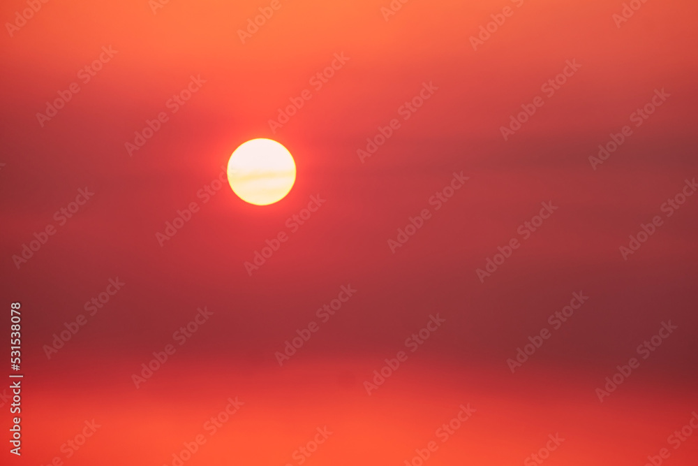 Obraz premium A big red sun in the sunset sky, a summer landscape. Evening sky in hot sunlight