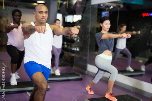 Man with others doing step aerobics in a fitness club