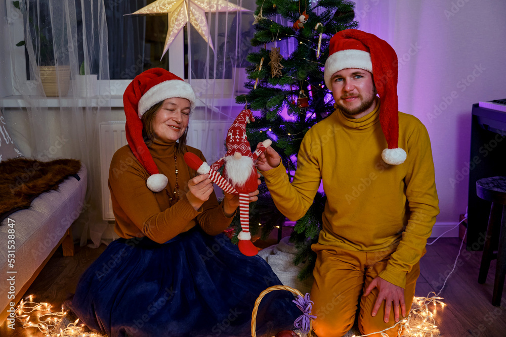 An adult man and a woman play a homemade puppet show at the Christmas tree. Home family leisure with a Christmas story on New Year Eve in the evening living room