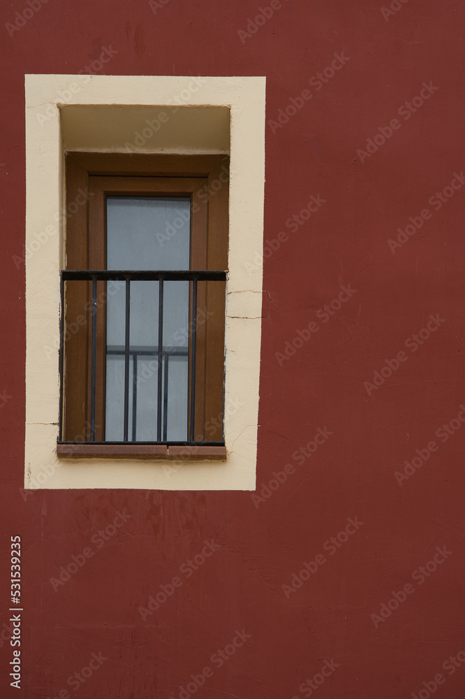 Colorful red colored facade with window details on a Latin Colonial building.