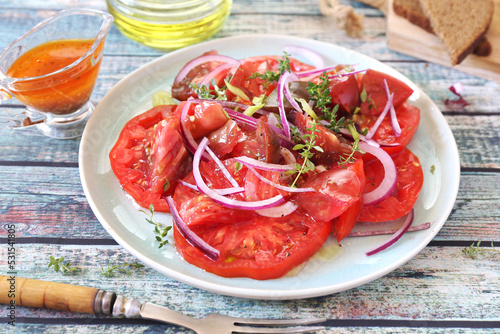 Tomato salad with red onion and spicy sauce of different varieties of tomatoes, two slices of rye bread