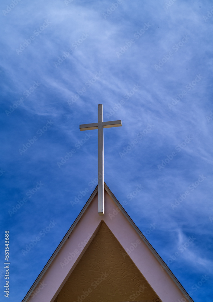 Tan Arched  Steeple with a White Cross Under Blue Sky with Cirrus Clouds.