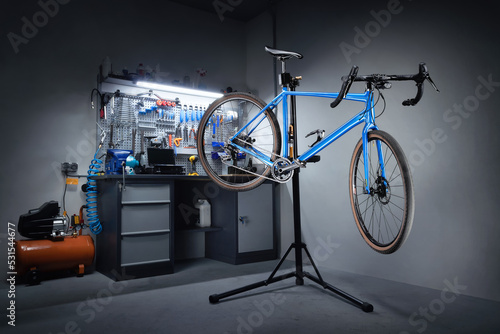 Bicycle workshop for repairing bicycles. Bicycle hanging on a repair stand in the background of a workbench with professional tools. Bicycle service.