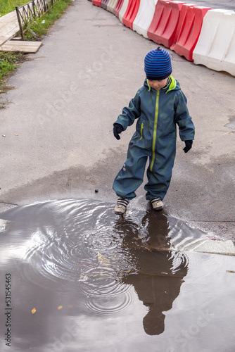 A two-year-old boy plays with a puddle in his hands maple leaves, autumn fun