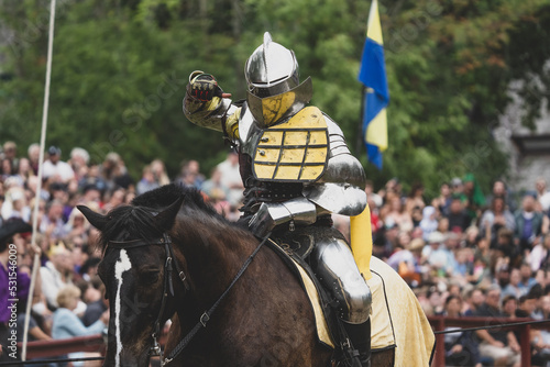 unknown knight in a suit of armor is riding on a horse and ready for battle photo