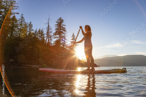 Adventurous Woman Paddling on a Paddle Board in a peaceful lake.