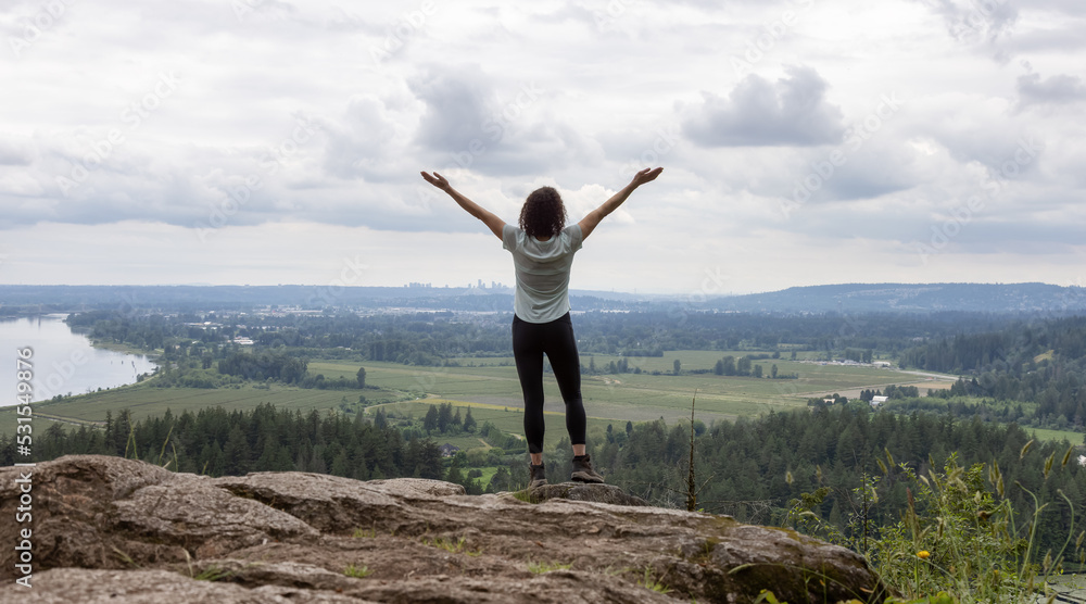 Adventurous Woman Standing on top of a rock overlooking the Canadian Nature Landscape. Adventurous Woman Standing on top of a rock overlooking the Canadian Nature Landscape.