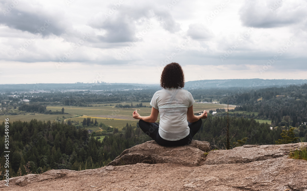 Adventurous Woman in Meditation overlooking the Canadian Nature Landscape.