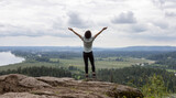 Adventurous Woman Standing on top of a rock overlooking the Canadian Nature Landscape.