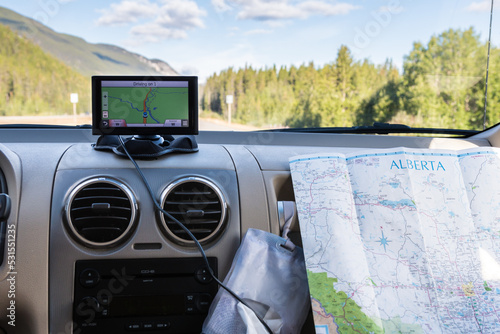 Using a GPS and paper road map on car trip. GPS navigation drive assistant and road map.  Vacation and travel in Alberta, Canada