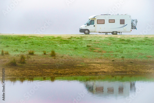 Camper rv camping at lake shore. Foggy day