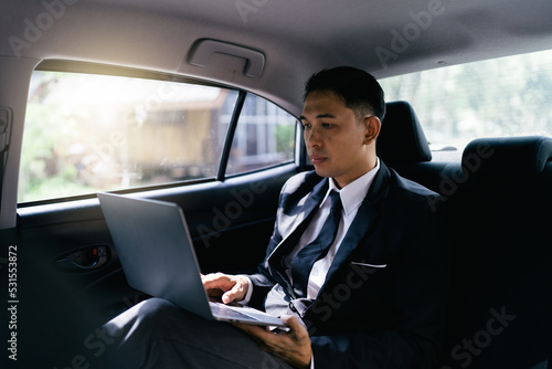 Asian businessman working on his laptop in the car. © PaeGAG