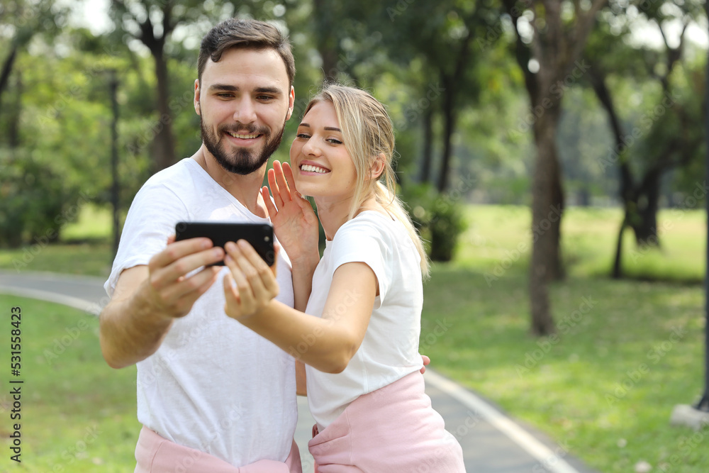 young caucasian couple in love using smart mobile phone portrait themself in the park (relaxation with technology concept) young caucasian couple in love using smart mobile phone portrait themself in the park (relaxation with technology concept)
