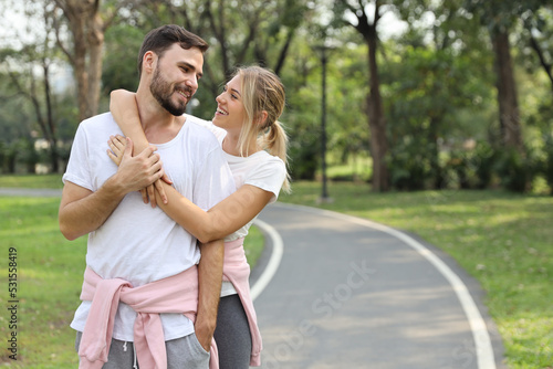 young couple caucasian people are in love. man and girl wearing white shirt hugging in the park during summer season with smiling and happy face © feeling lucky